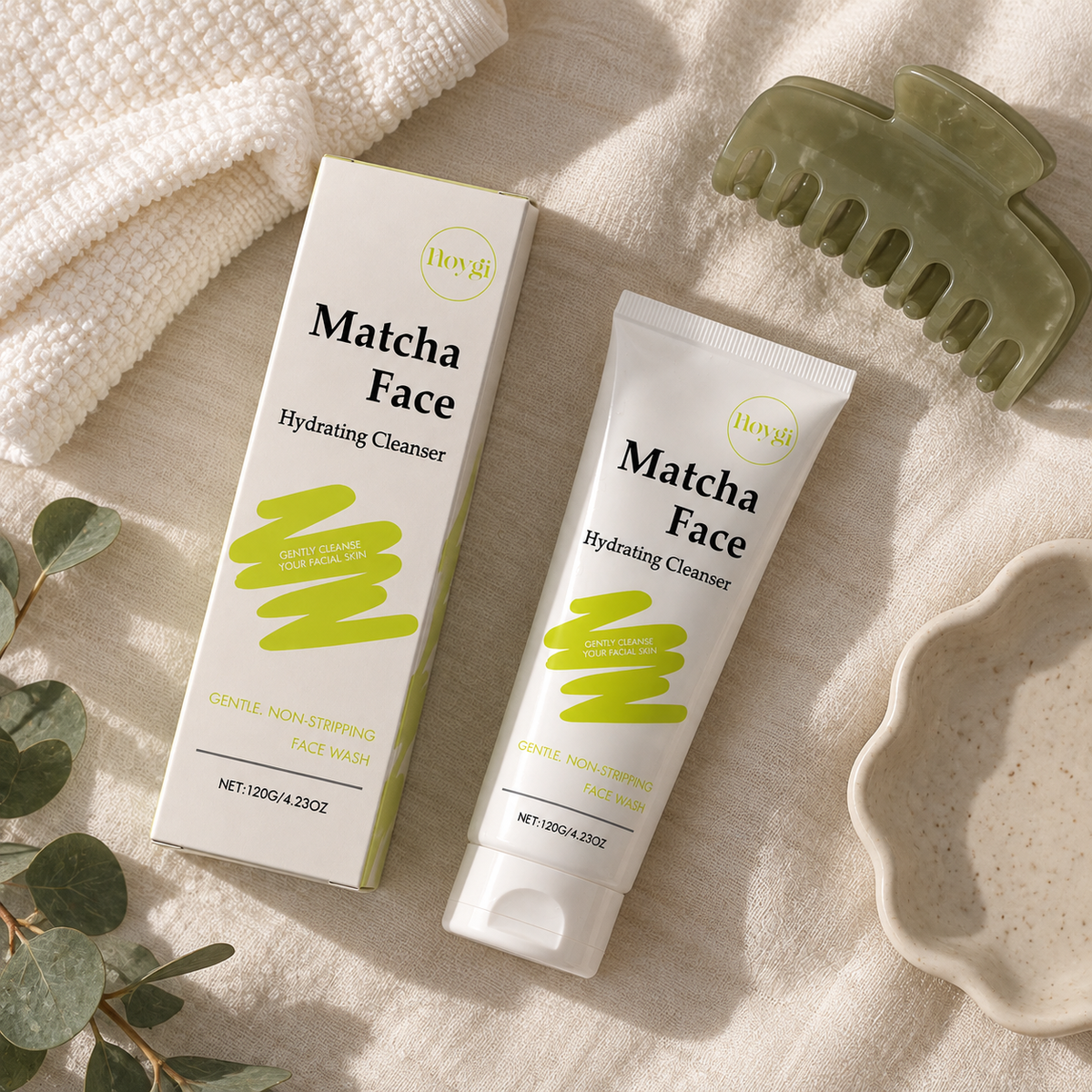 Matcha face cleanser tube and box flat lay with a towel, claw clip and dish