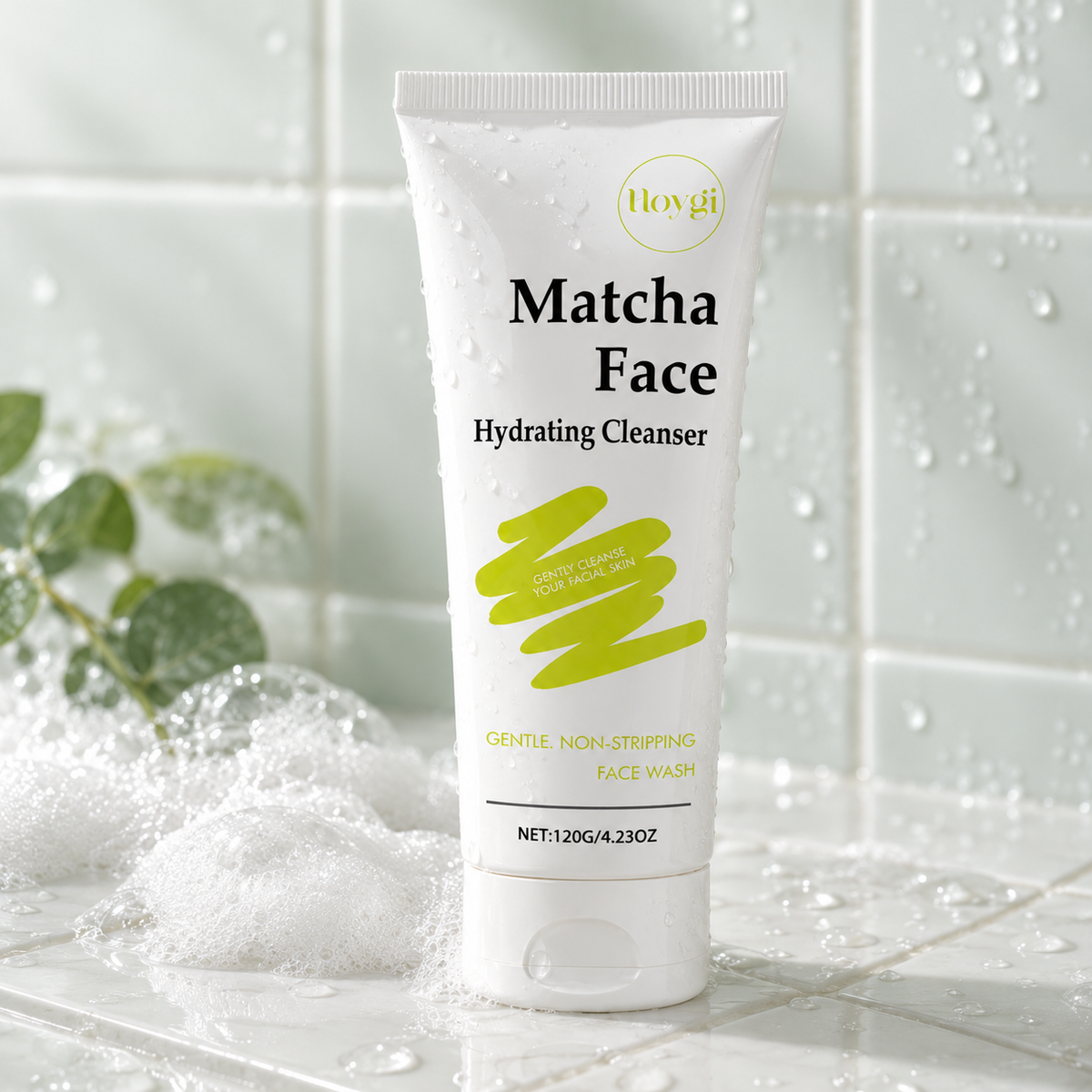 Matcha face cleanser tube with water droplets and foam on a tiled surface